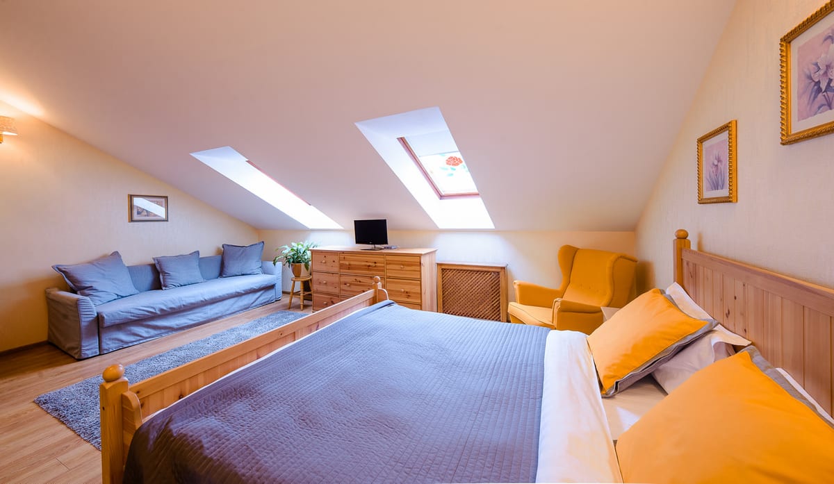 Mansard studio in pine with a double bed, a sofa and an orange armchair