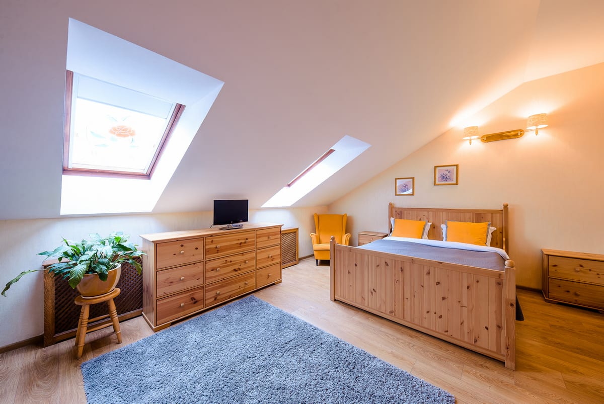 Mansard studio in pine with a chest of drawers, a skylight and a blue rug