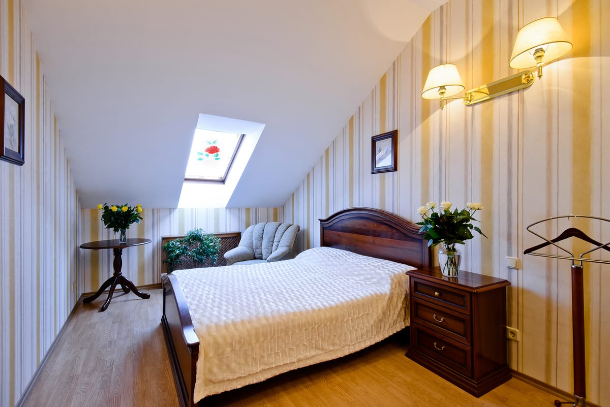 Mansard bedroom from the doorway, an armchair and small table beneath the skylight