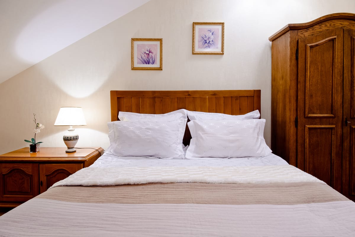 Cream mansard bedroom with a wooden headboard and a tall wardrobe