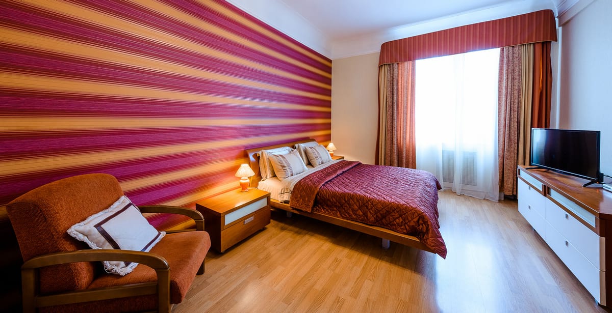 Purple-and-gold striped room with a bed, an armchair, a coffee table and a television