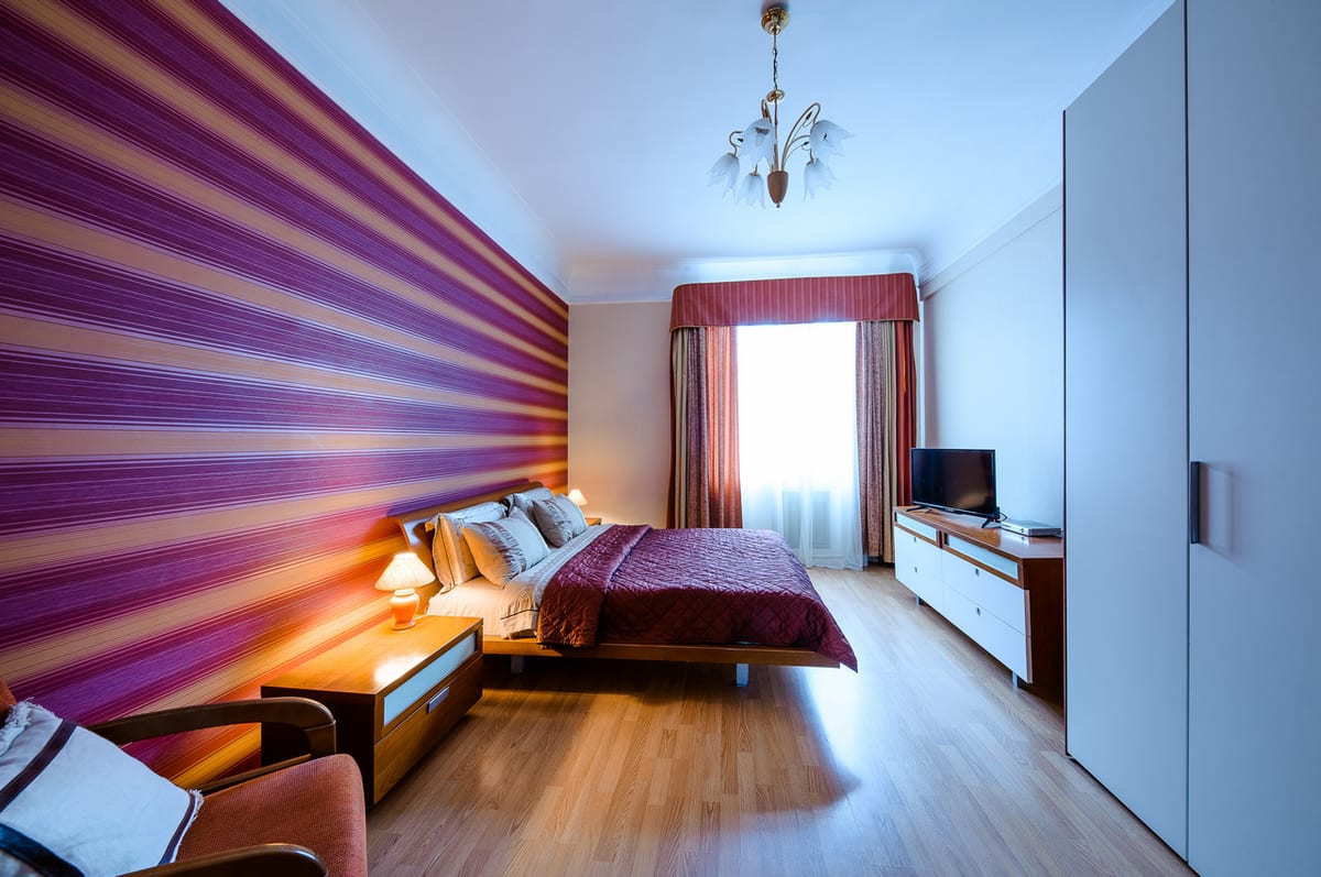 Striped room from the window end, wardrobe and television along the far wall