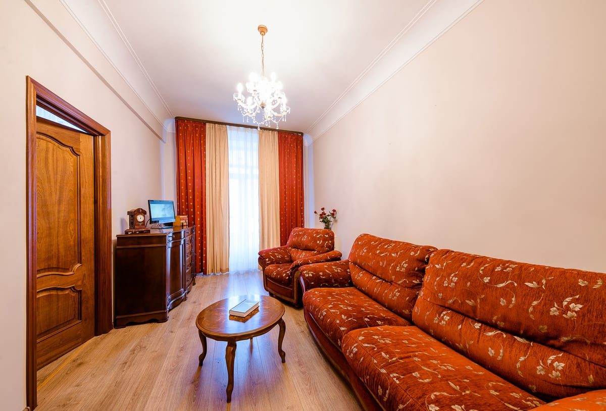 Sitting room with an orange three-piece suite, a chandelier and a wooden double door