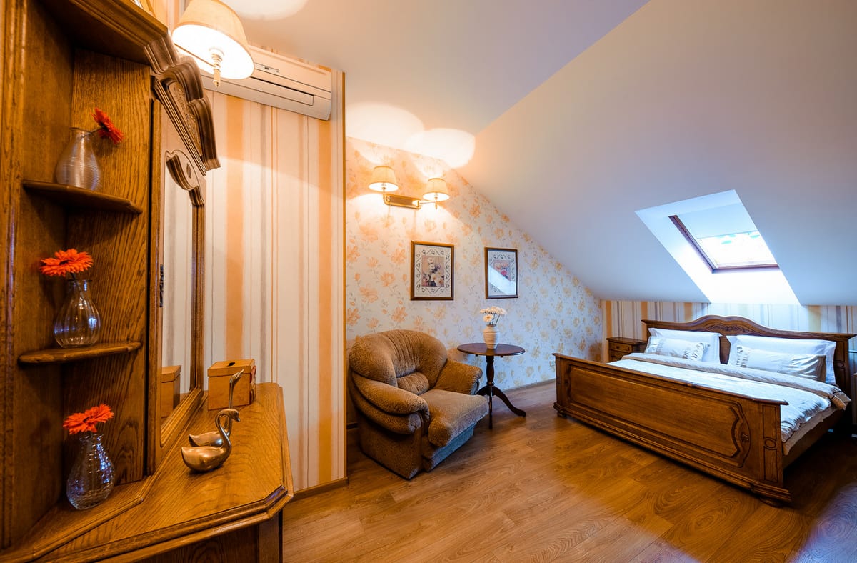 Mansard room with shelves of gerberas, an armchair and the bed under the roof slope