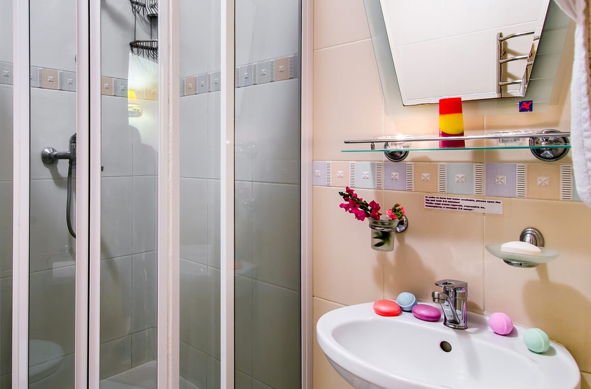 Bathroom with a corner shower cubicle, a basin and coloured soaps