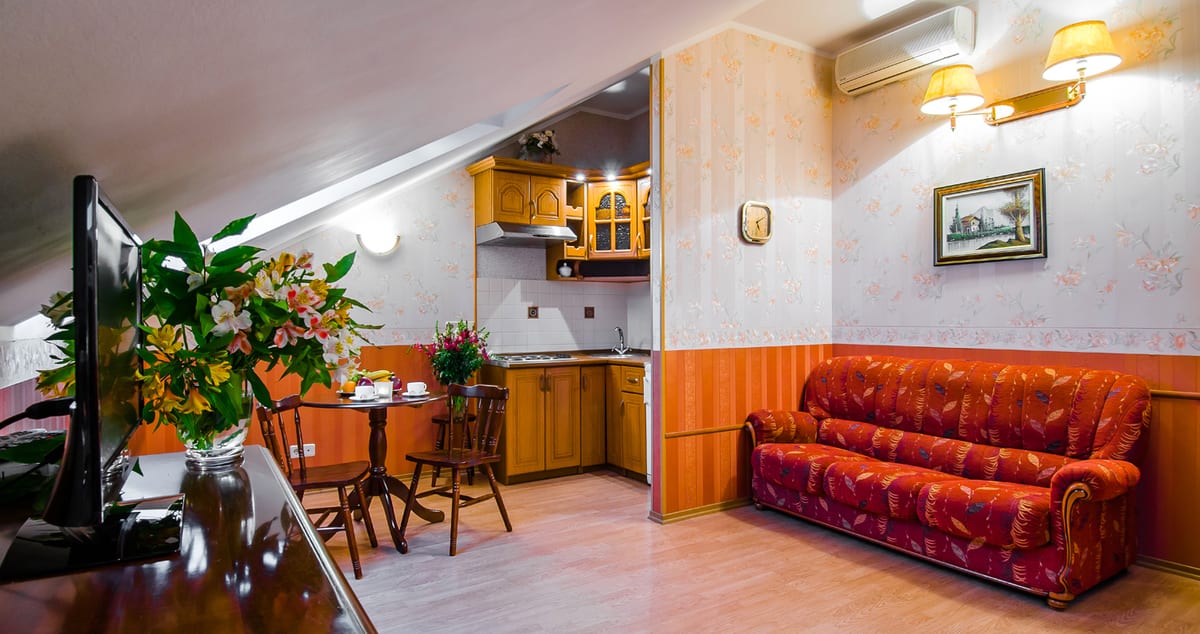 Mansard studio with a kitchenette, a dining table and a red leather sofa