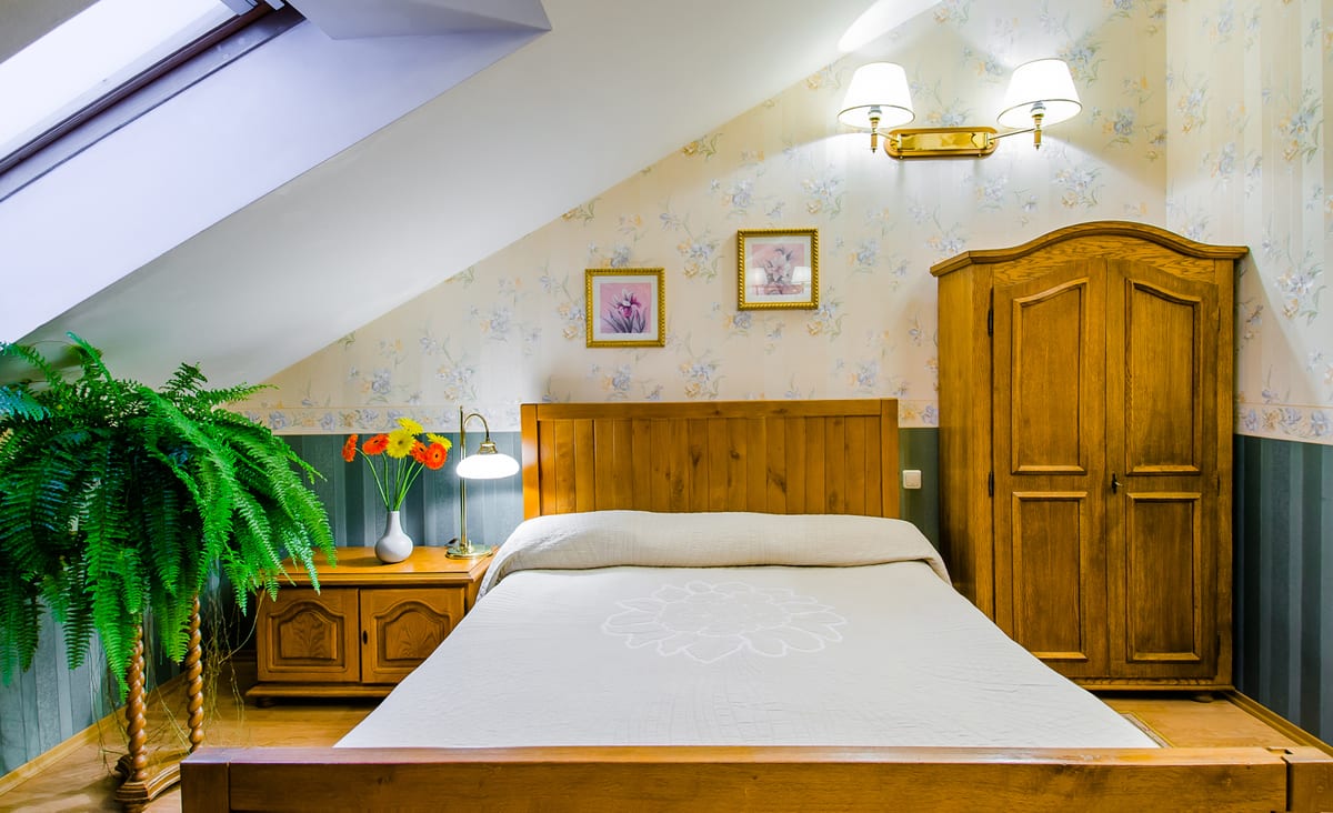 Mansard bedroom with green panelling, ferns and a wooden wardrobe