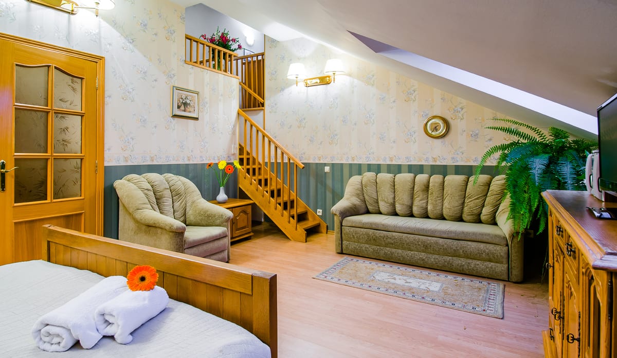 Mansard studio with an internal wooden staircase, a sofa and an armchair