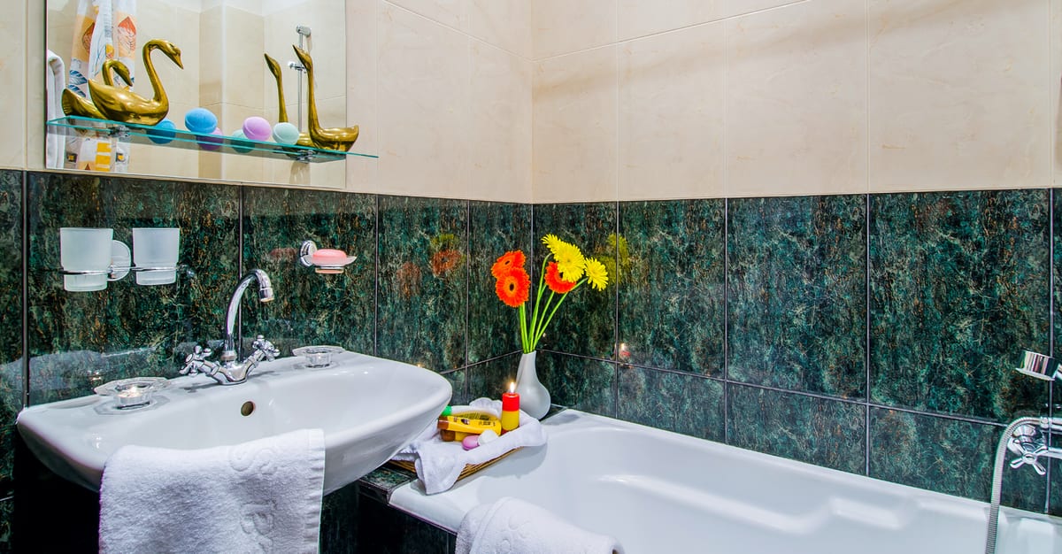 Green marble bathroom with a bath, a pedestal basin and a breakfast tray