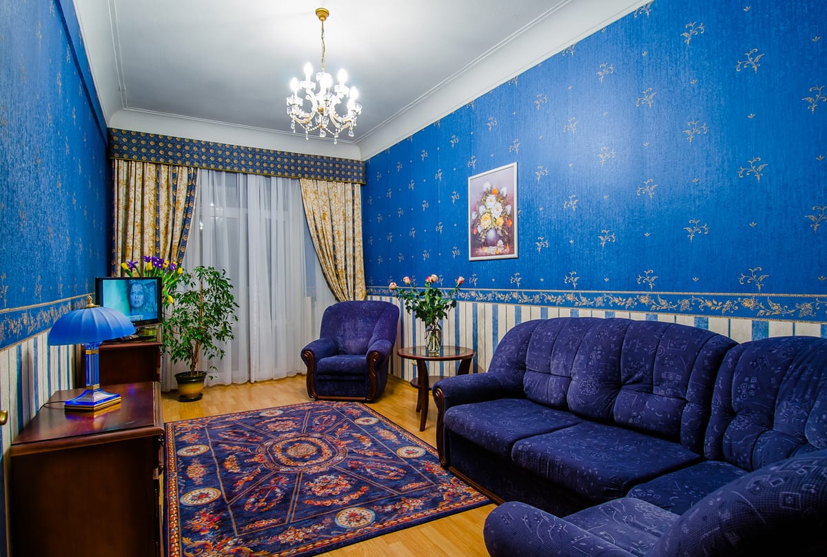 Sitting room with a blue upholstered suite, a patterned rug and a chandelier