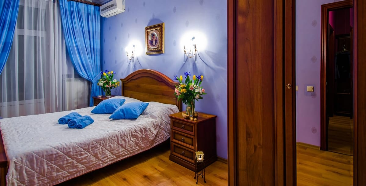 Lilac bedroom with turquoise cushions and irises on the bedside table