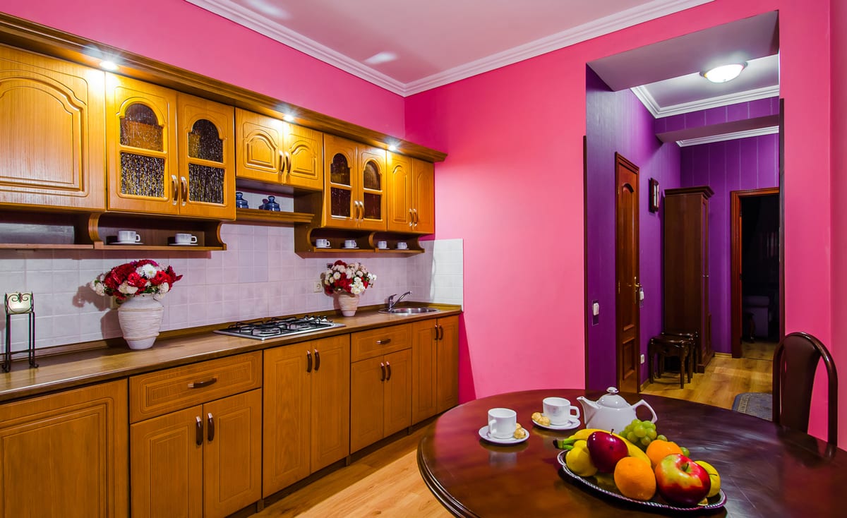 Kitchen with wooden units, a gas hob and a round table laid with fruit and coffee