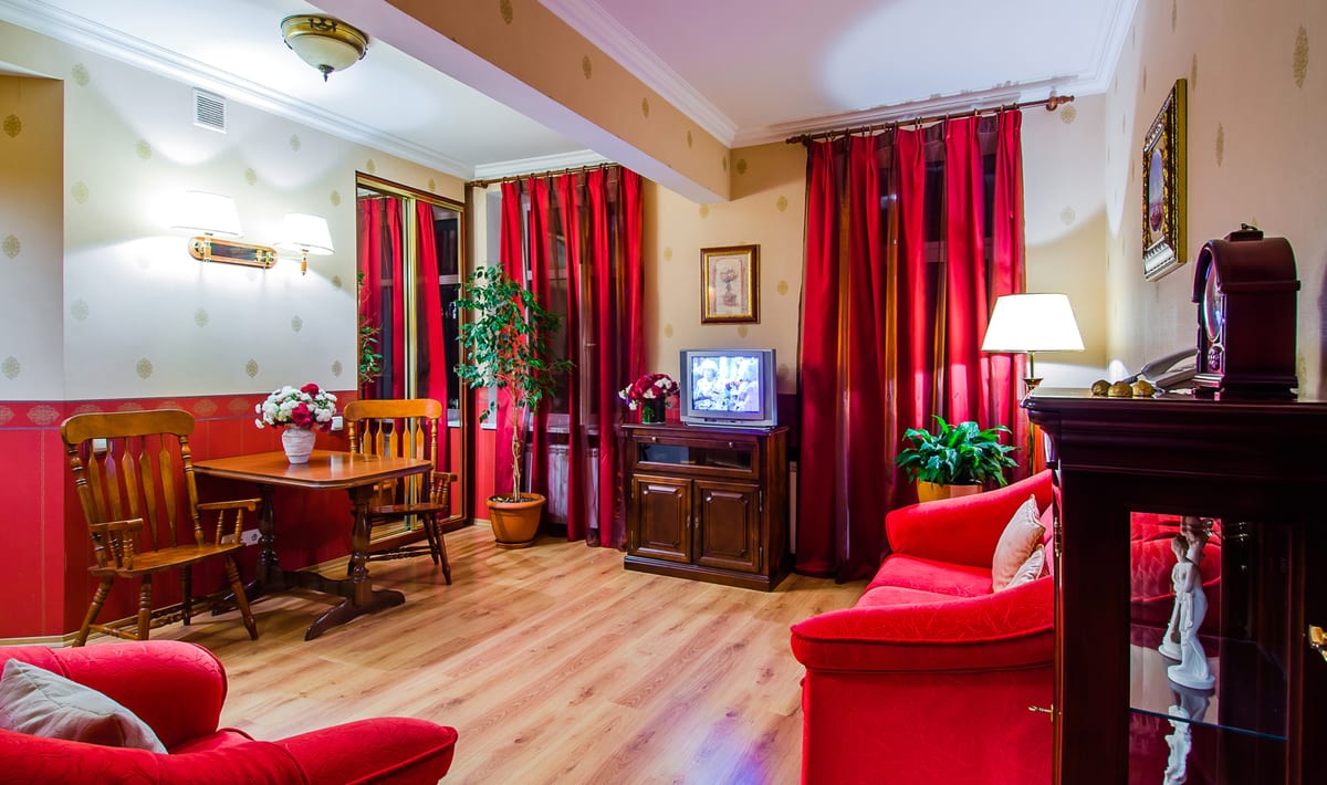 Red sitting and dining room with a dining table, a television and armchairs