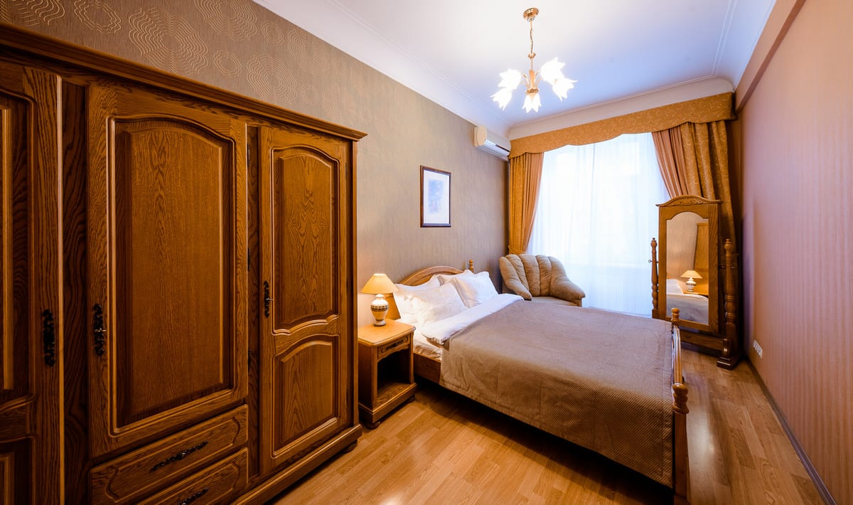 Bedroom with a large oak wardrobe, a chandelier and a beige bedspread