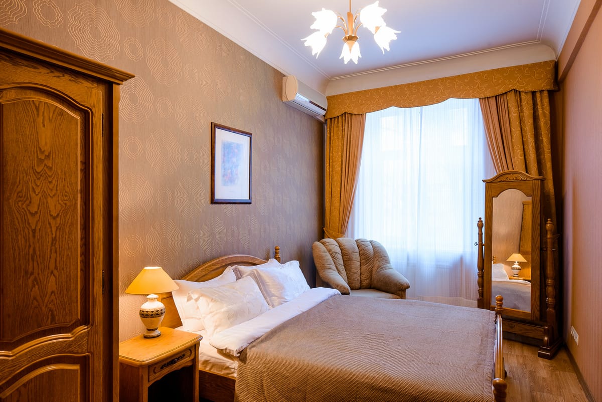 Bedroom with an oak wardrobe, a cheval mirror and a lamp on the bedside table