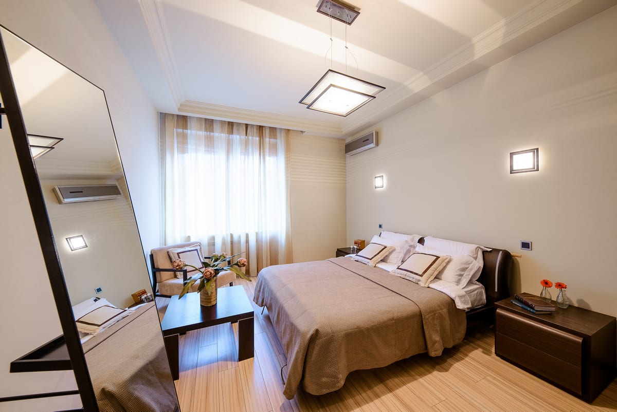Bedroom in grey and cream with a full-length mirror and a low chest