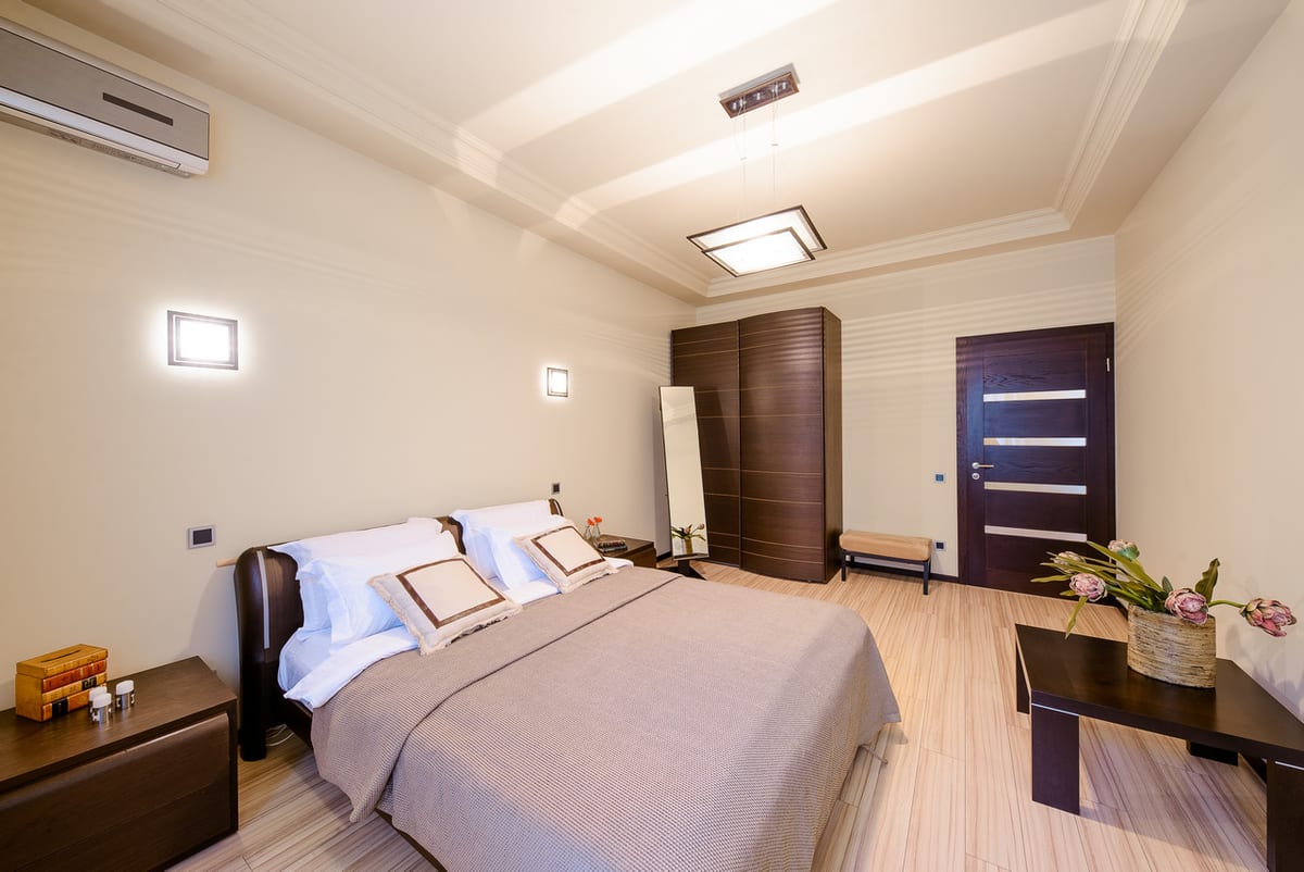Bedroom with a dark wardrobe, a blanket box and pale wood flooring