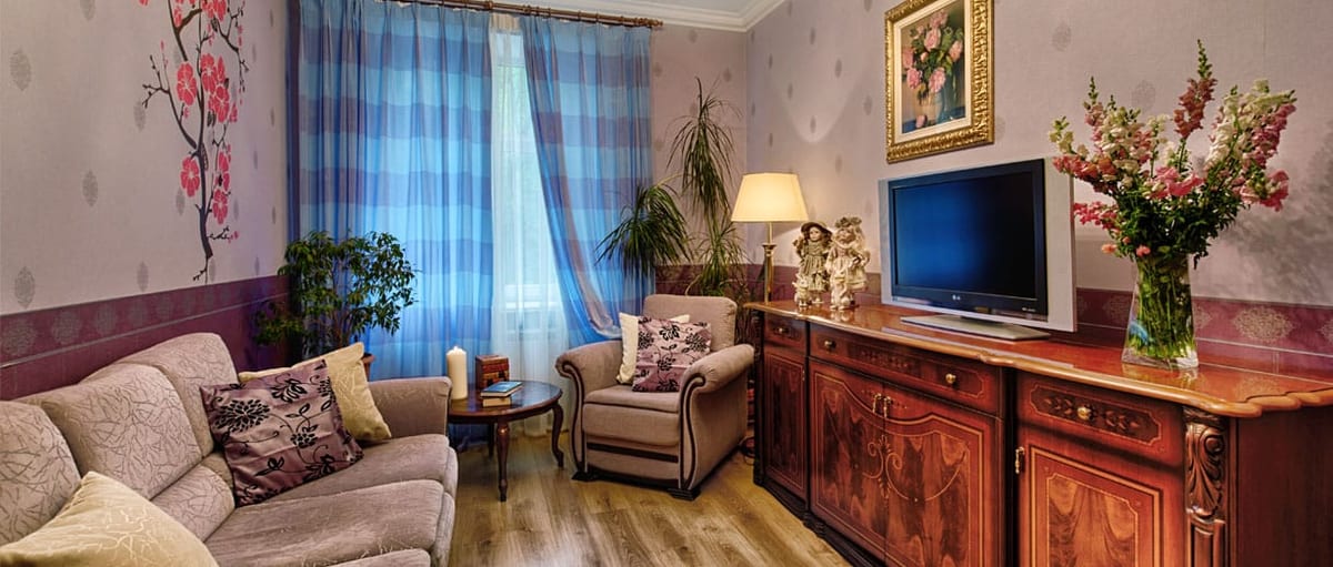 Lilac sitting room with a sideboard, cut flowers and an armchair