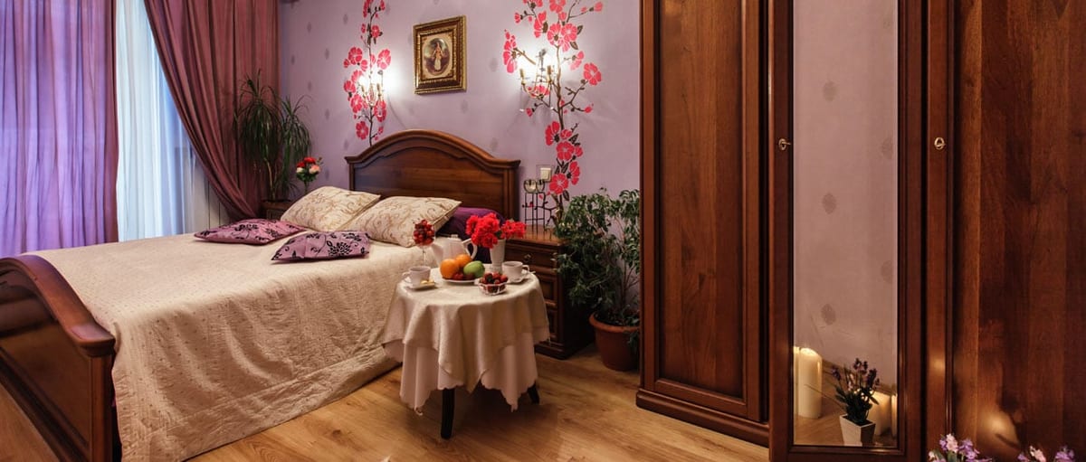 Cherry-blossom wallpaper behind the bed, with a wardrobe and a chandelier