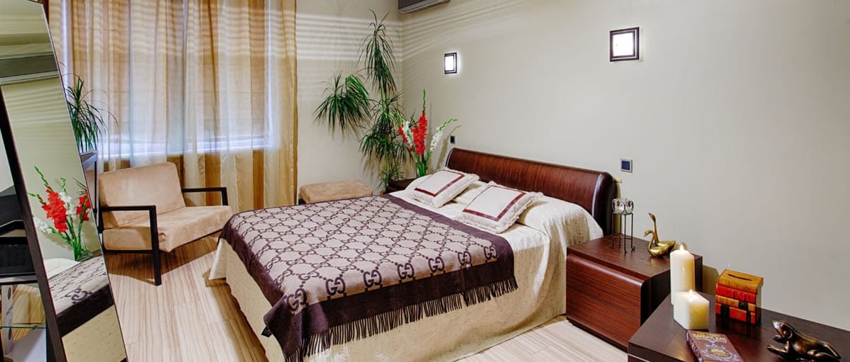 Cream bedroom with a monogrammed bedspread, a mirror and candles