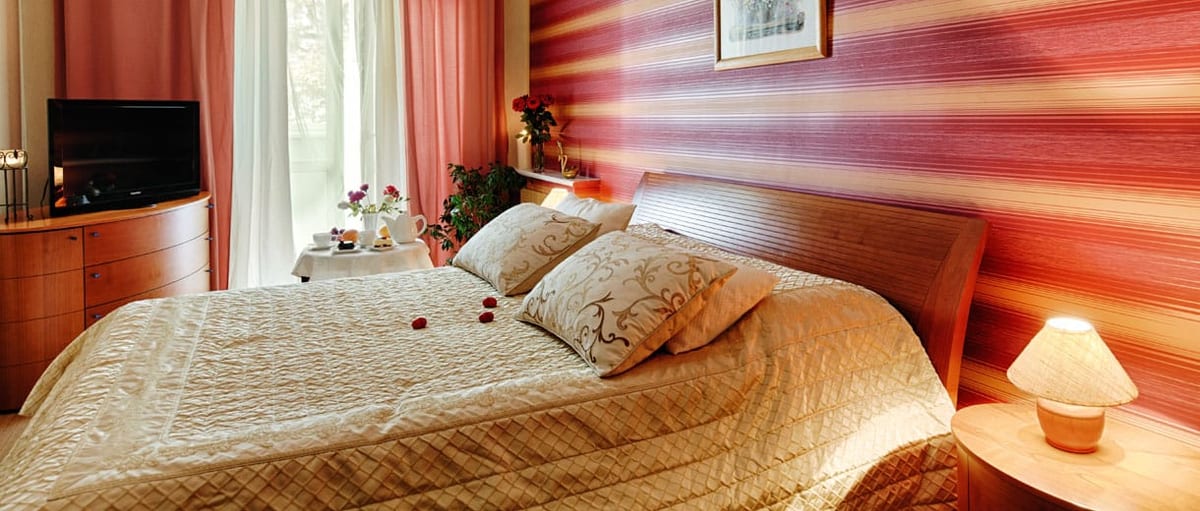 Coral-striped bedroom with a gold bedspread and a bay window
