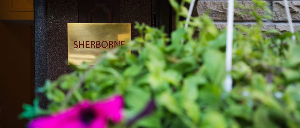 The brass SHERBORNE nameplate on the door, framed by petunias