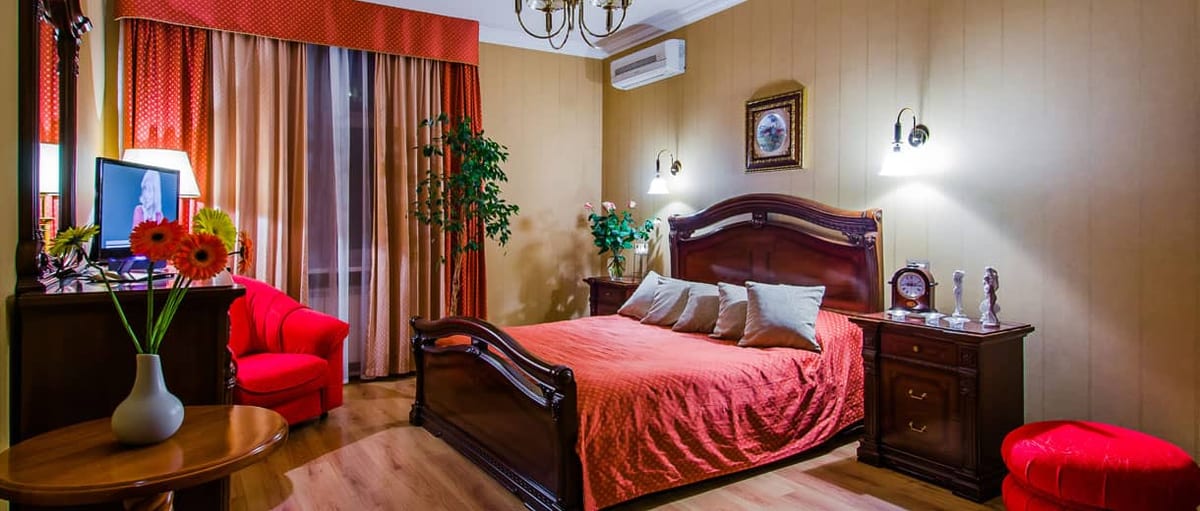 Ochre bedroom with a red bedspread and a red sofa at the foot of the bed