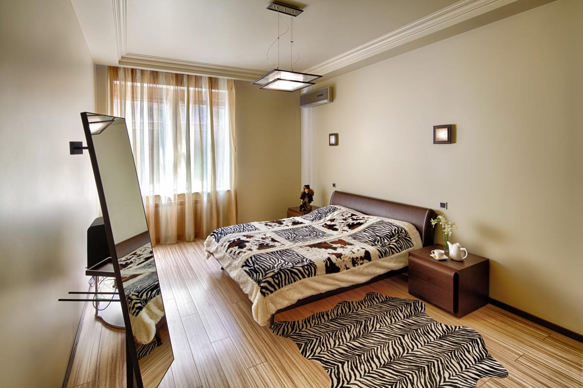 Bedroom with a zebra-print rug and bedspread, a mirror and a bedside tea tray