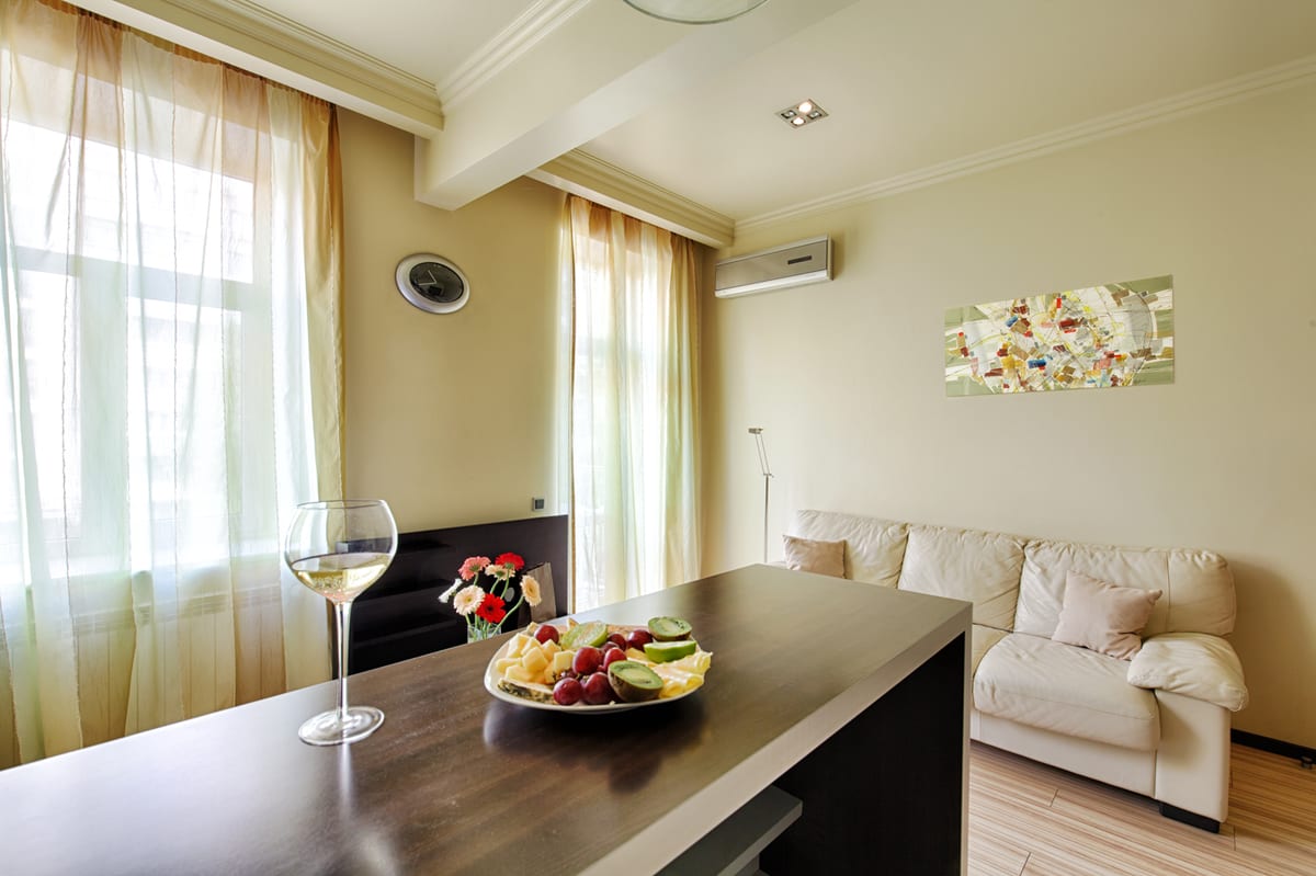 Living room with a dark dining bar, fruit and a glass of wine, cream sofa behind