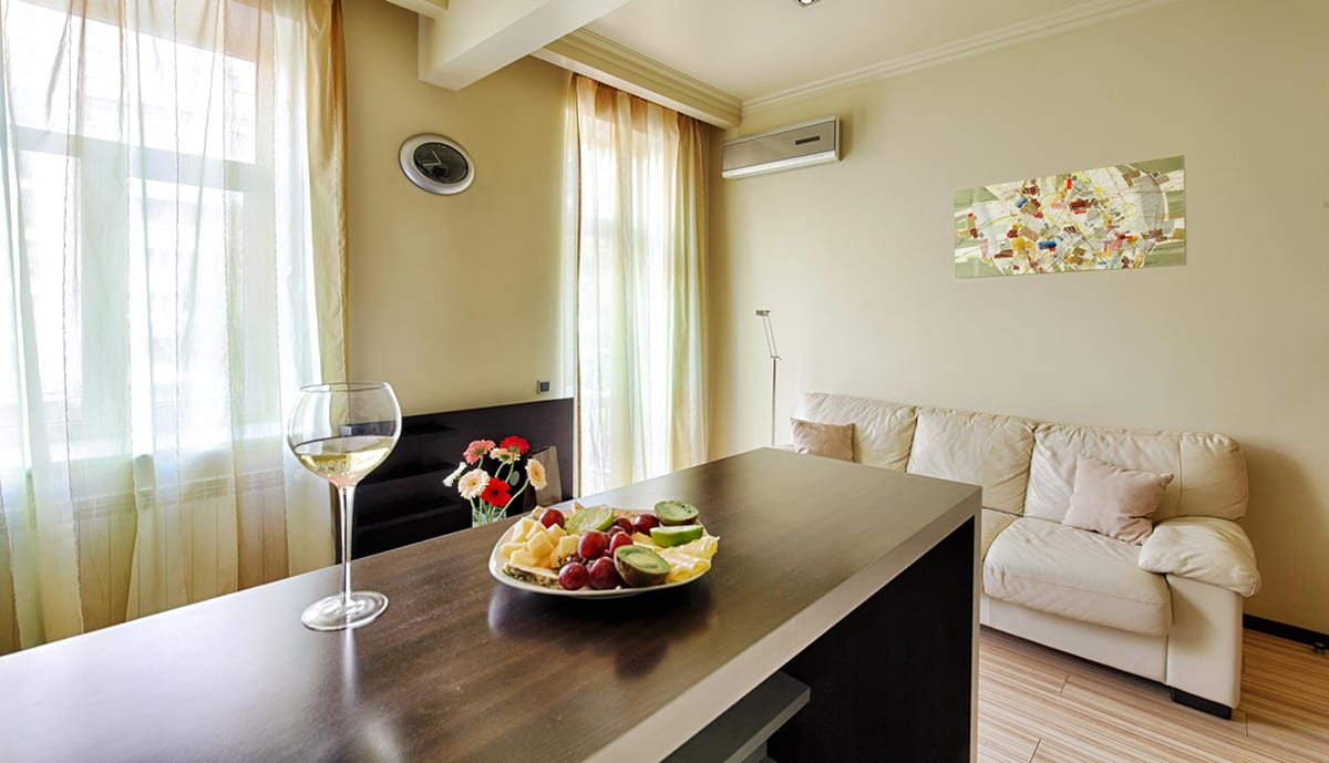 Living room with a dark dining bar, fruit and wine, cream sofa behind