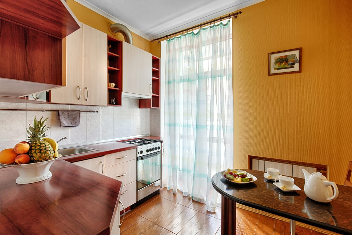 Kitchen with an orange wall, a cooker and a table laid with fruit and a teapot