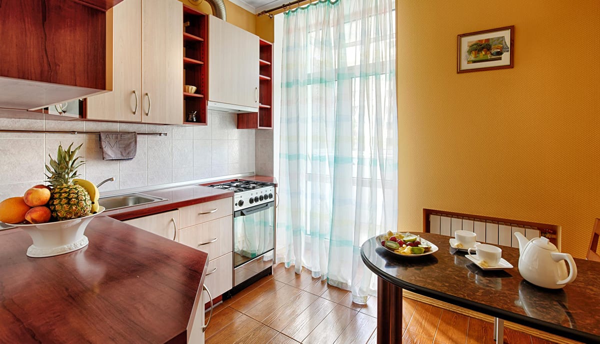 Orange kitchen with a table laid with fruit and a teapot