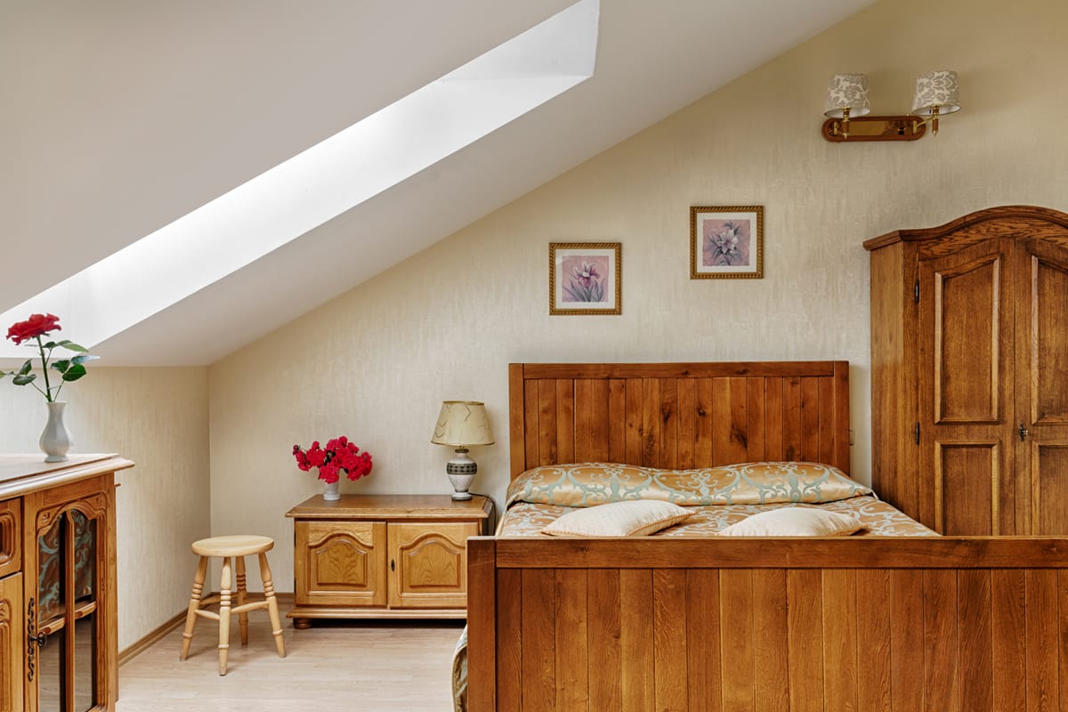 Pine mansard bedroom with a skylight above the bed and red carnations