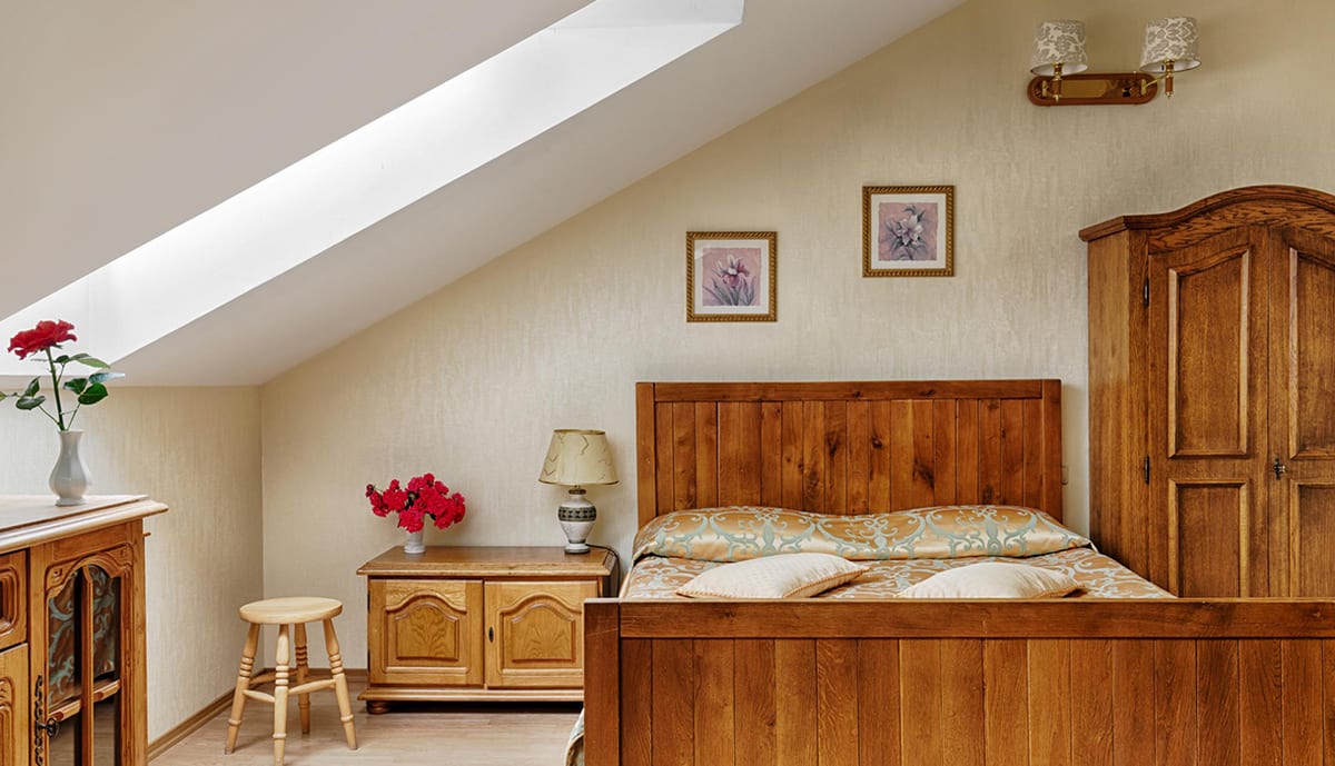 Pine mansard bedroom with red carnations and a skylight over the bed
