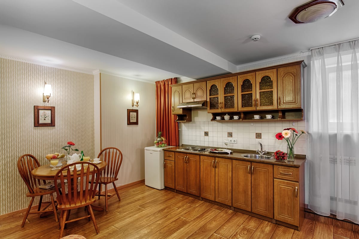 Kitchen with wooden wall units, a round dining table and cut carnations