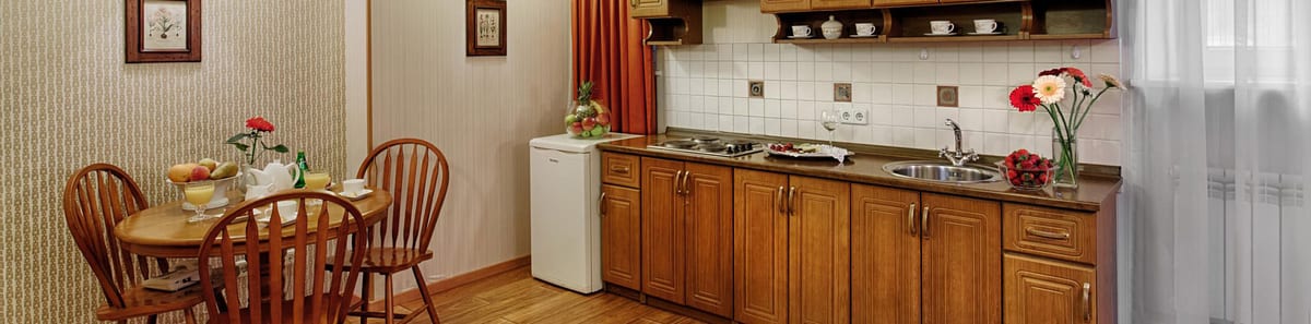 Wooden kitchen seen wide, round dining table and cut carnations