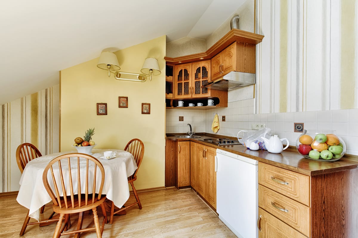 Kitchen with a yellow wall, a laid round table and a bowl of apples