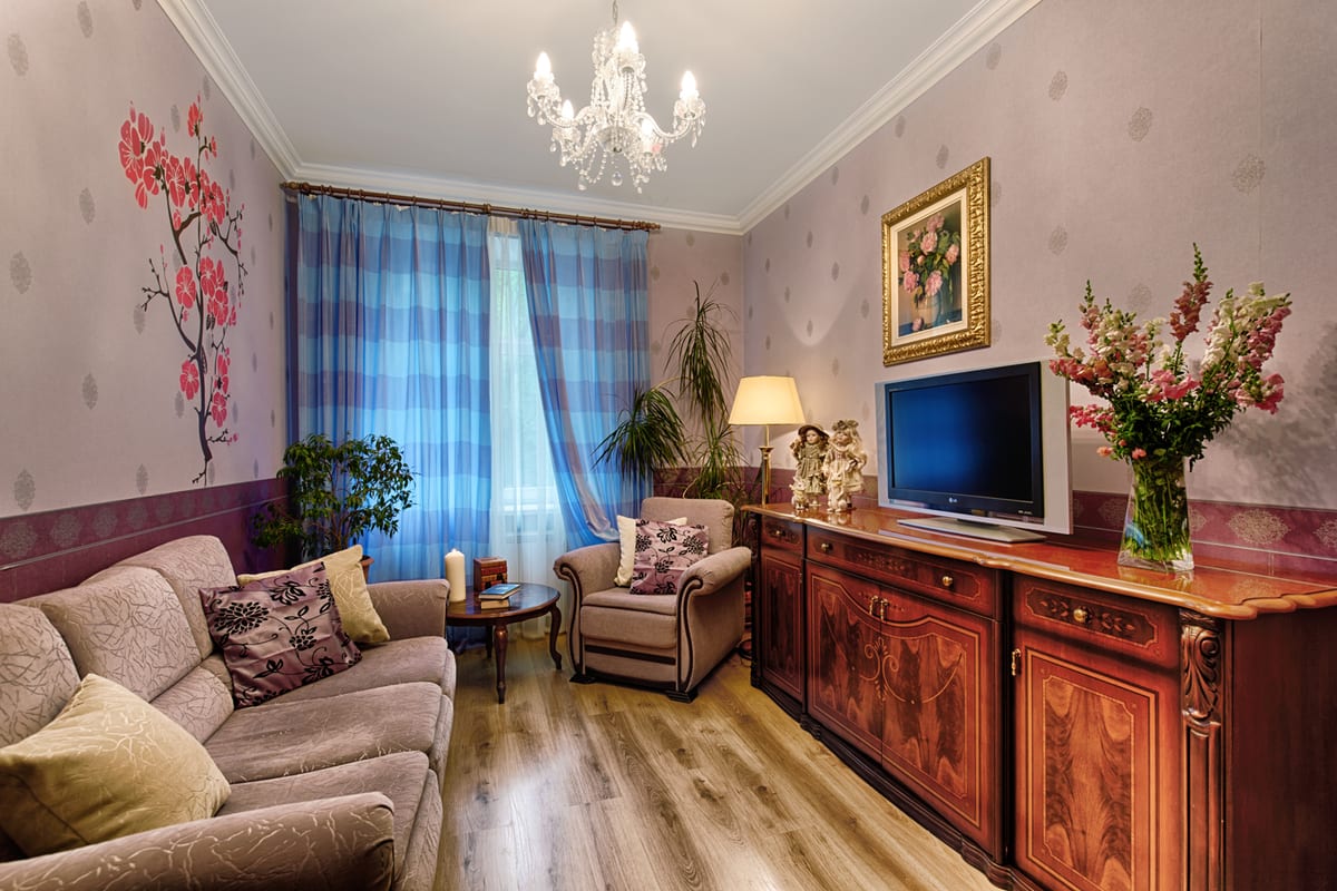 Sitting room with a corner sofa, blue check curtains and a carved sideboard