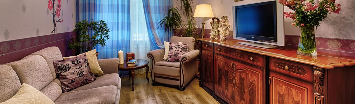 Sitting room seen wide, corner sofa and blue check curtains at the window