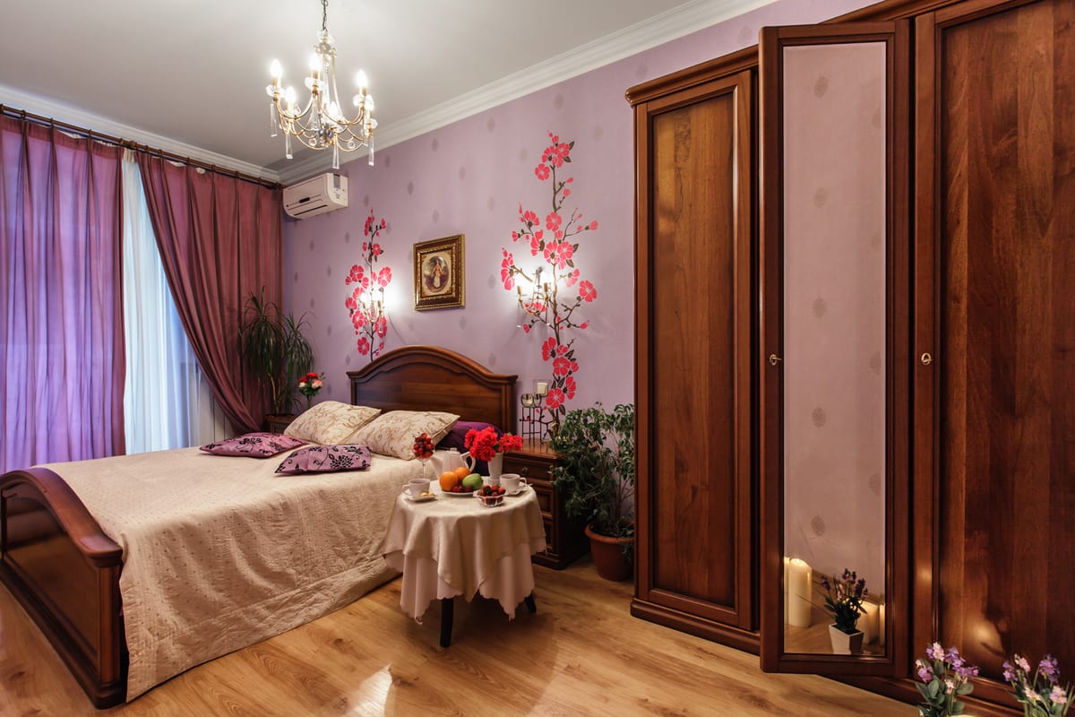 Bedroom with a chandelier, cherry-blossom wallpaper, a wardrobe and roses on the table