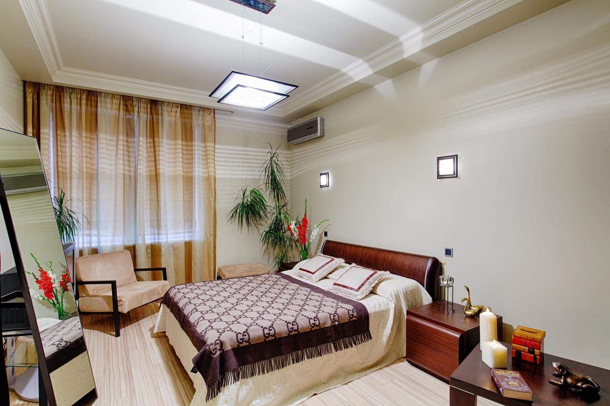 Cream bedroom with a monogrammed bedspread, a mirror and lit candles