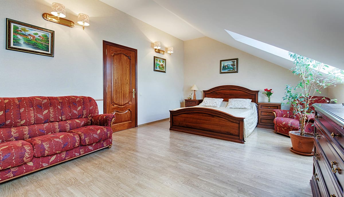 Mansard room with a red patterned sofa beside the double bed