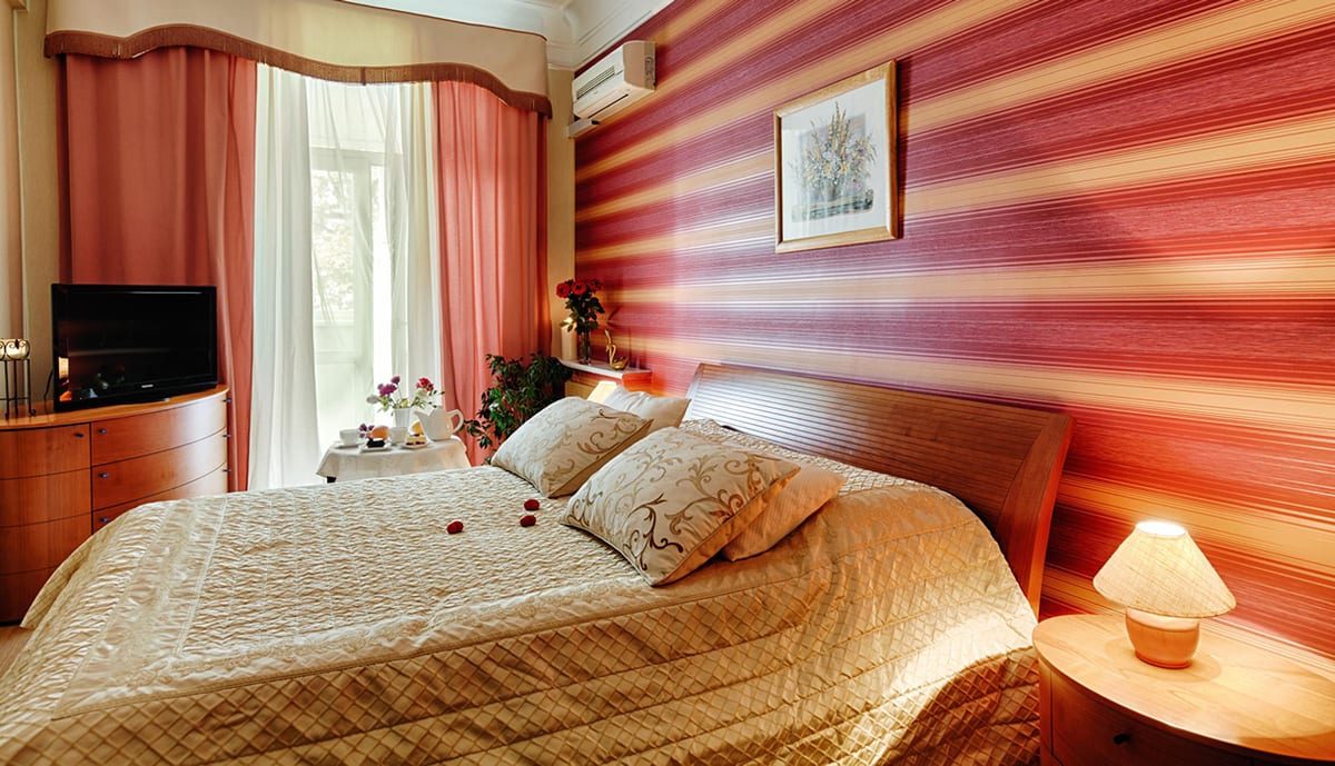 Coral-striped bedroom with a gold bedspread beside the bay window