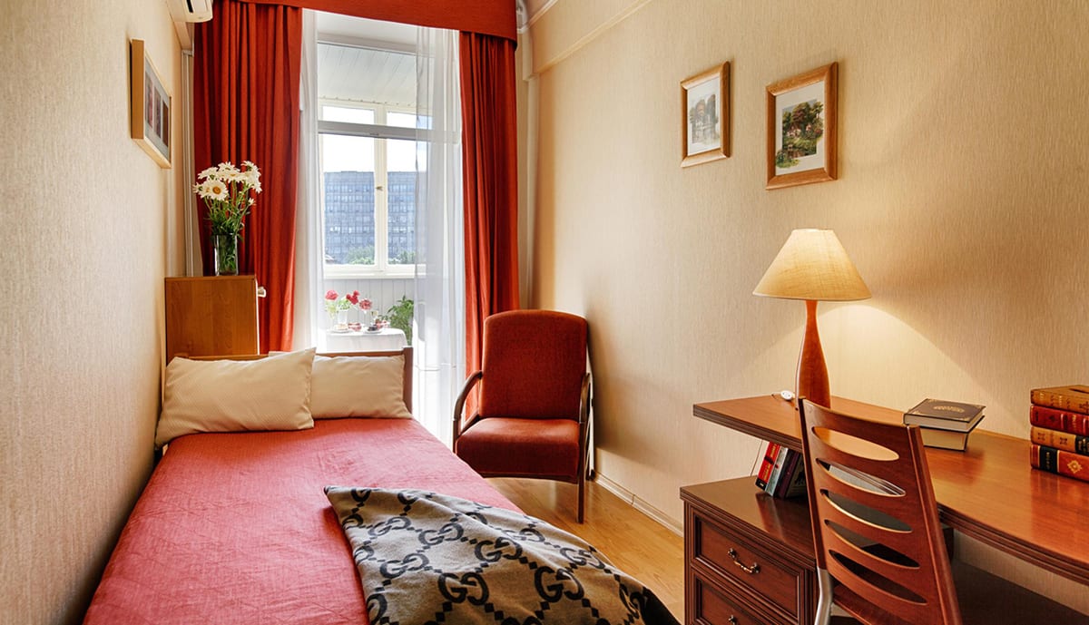 Coral daybed with a writing desk and books beside the window