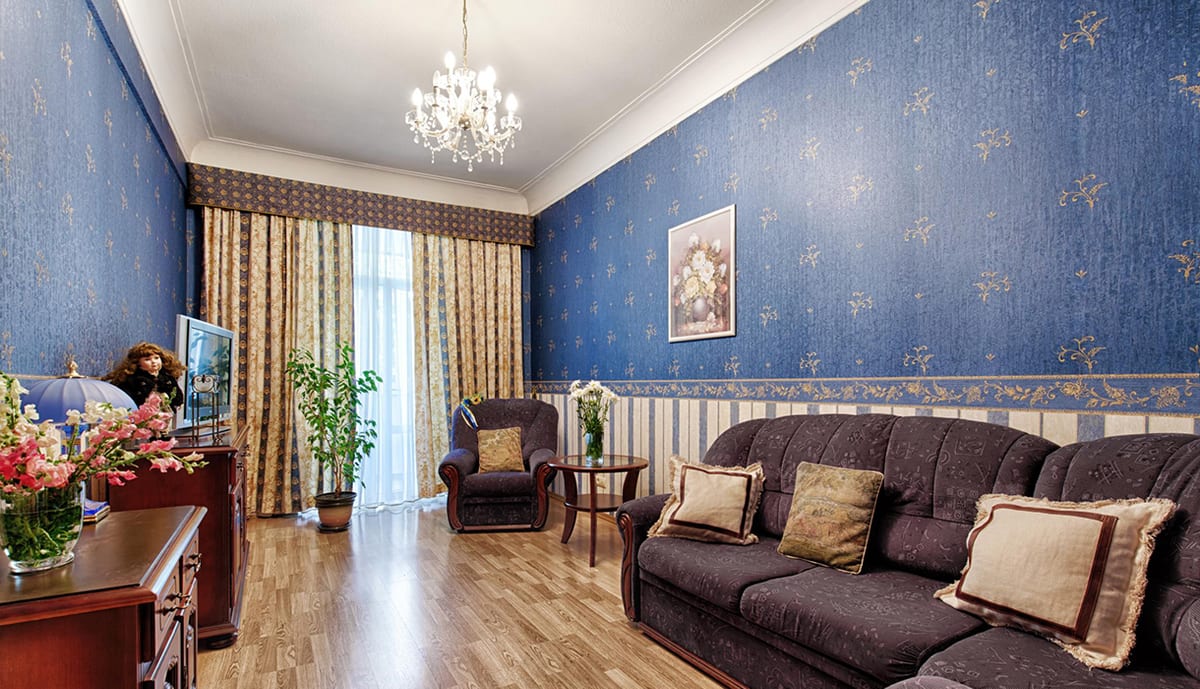 Sitting room with a cobalt damask wall, a brown sofa and a chandelier