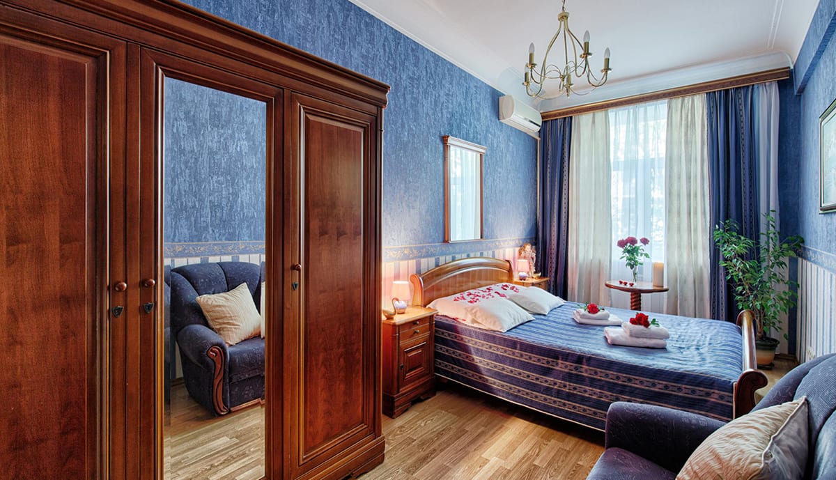Bedroom with a cobalt damask wall, a mirrored wardrobe and a blue bedspread