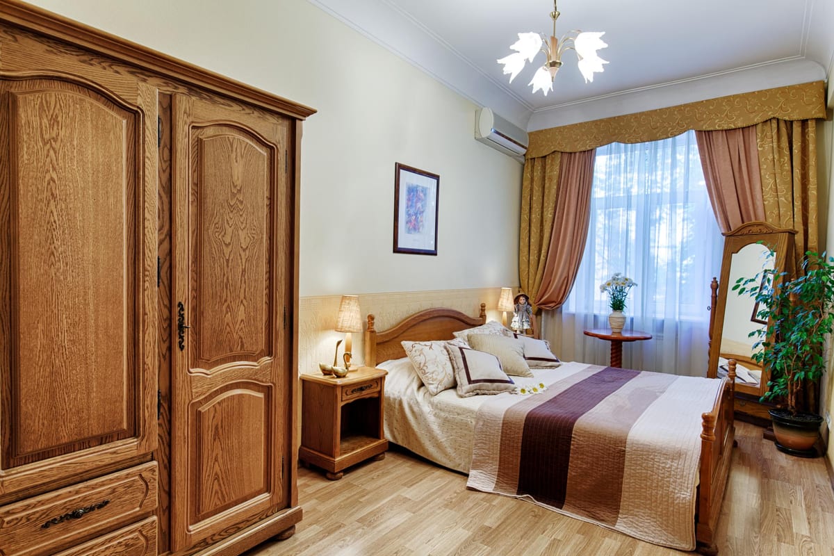 Bedroom with a large oak wardrobe, a brown-and-cream bed runner and a cheval mirror