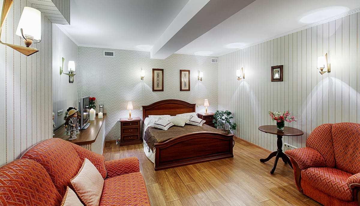 Pale green panelled room with a double bed and coral armchairs