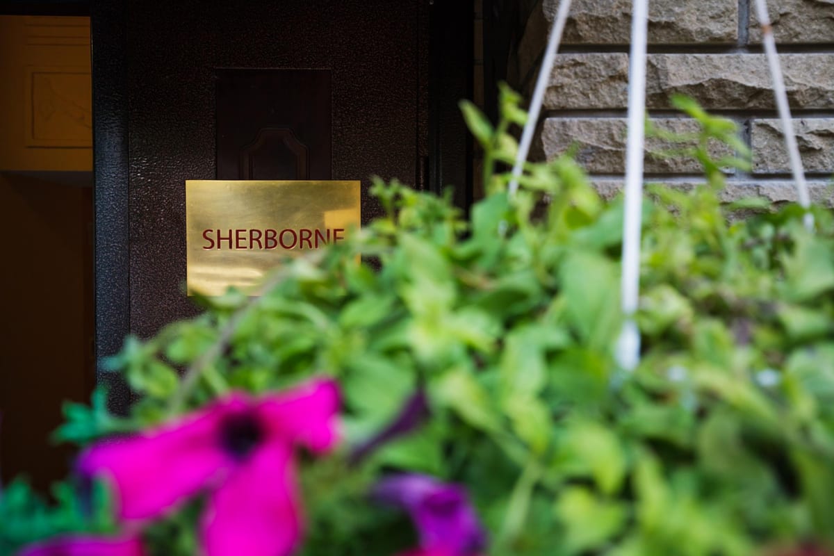 Brass SHERBORNE nameplate on the door, seen through petunias