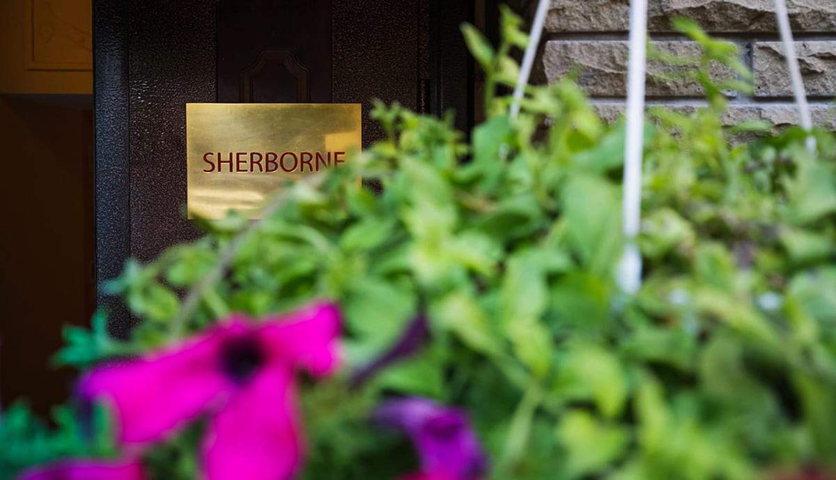 Brass SHERBORNE nameplate beside the door, petunias in the foreground